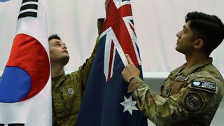 Private Kieran Findlay and UNC Honor Guard Company Commander Captain Zachary Balitaan prepare the Republic of Korea and Australian flags in the Honor Guard drill hall in Pyeongtaek, Republic of Korea