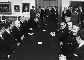 View of the Soviet delegation (on left) and United States negotiating team (on right) sitting together at a long table during Strategic Arms Limitation Talks (SALT) in Vienna, Austria circa 1970