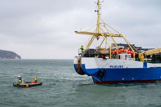 A fiber optic cable is pulled ashore from the cable-laying ship "Pleijel" at the entrance to the port of Sassnitz