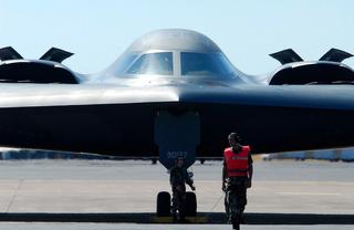 A US Air Force ground crew member completes his pre-fight checks on a B-2 Bomber that temporarily landed at RAAF Base Darwin for an 'engines running' crew change as part of the US Strategic Bomber Training Program