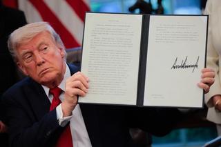 Donald Trump holding up signed EO
