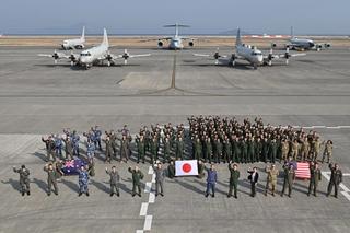 Australian, American, and Japanese personnel in a group photo on the tarmac at Marine Corps Air Station Iwakuni in Japan during a trilateral training and engagement activity.