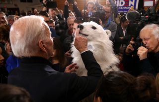 Democratic presidential candidate Joe Biden taps the nose of a person in a polar bear costume during a campaign event in New Hampshire, February 2020