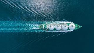 Aerial top view LNG Tanker ship (Liquified Natural Gas) with contrail in the ocean sea ship carrying container and running for export from container international port to custom ocean concept freight shipping by ship service