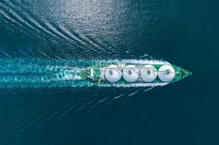 Aerial top view LNG Tanker ship (Liquified Natural Gas) with contrail in the ocean sea ship carrying container and running for export from container international port to custom ocean concept freight shipping by ship service