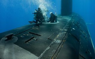 Divers attending to a submarine underwater.