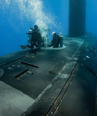 Divers attending to a submarine underwater.