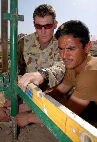 Australian Combat Engineer Sapper Brad Butson helps an Afghan National Army Engineer work on scaffolding while building a pergola, 2007 