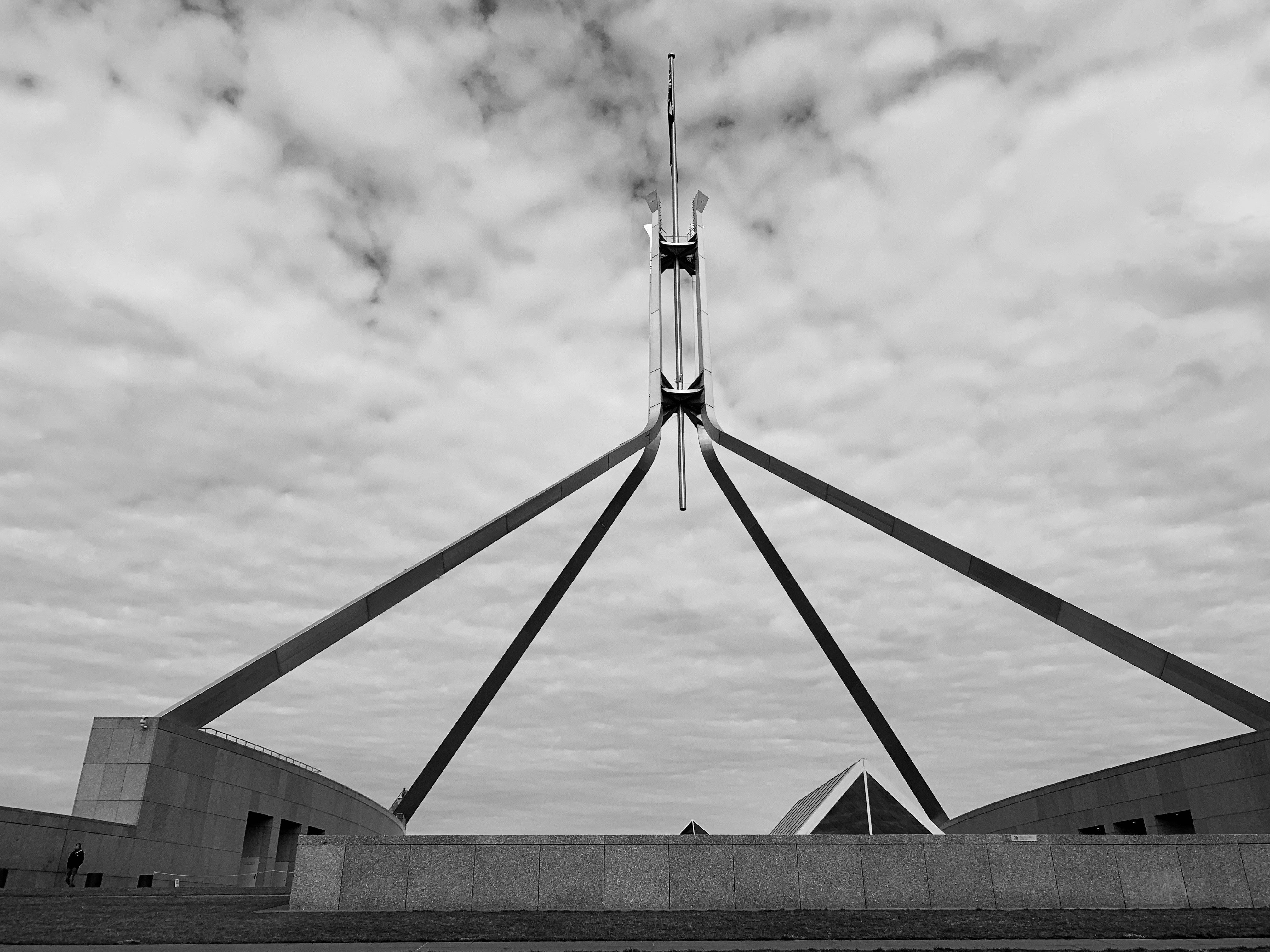 Greyscale photo of flag mast atop New Parliament House, Canberra.