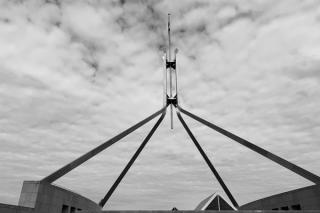 Greyscale photo of flag mast atop New Parliament House, Canberra.