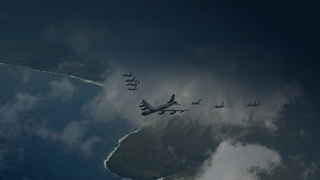 US and Japanese military aircraft flying in formation above ocean and coastline.