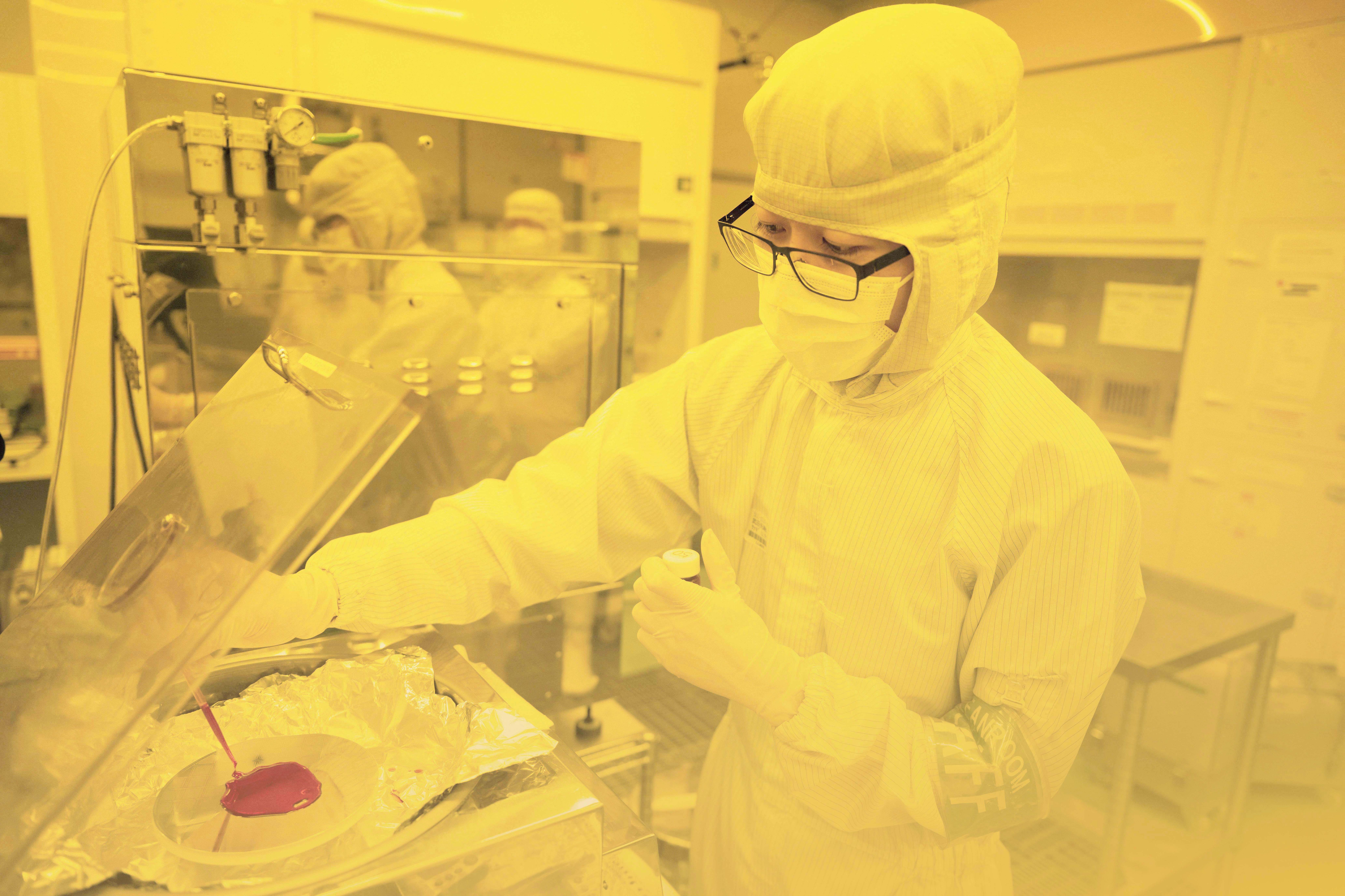 A person in protective wear in a laboratory preparing materials for semiconductors.