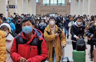 People wear face masks as they wait at Hankou Railway Station in Wuhan, China, January 2020