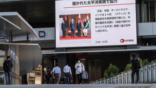 Pedestrians walk past a big screen displaying news about the Quad Leaders’ Summit, Tokyo, May 2022
