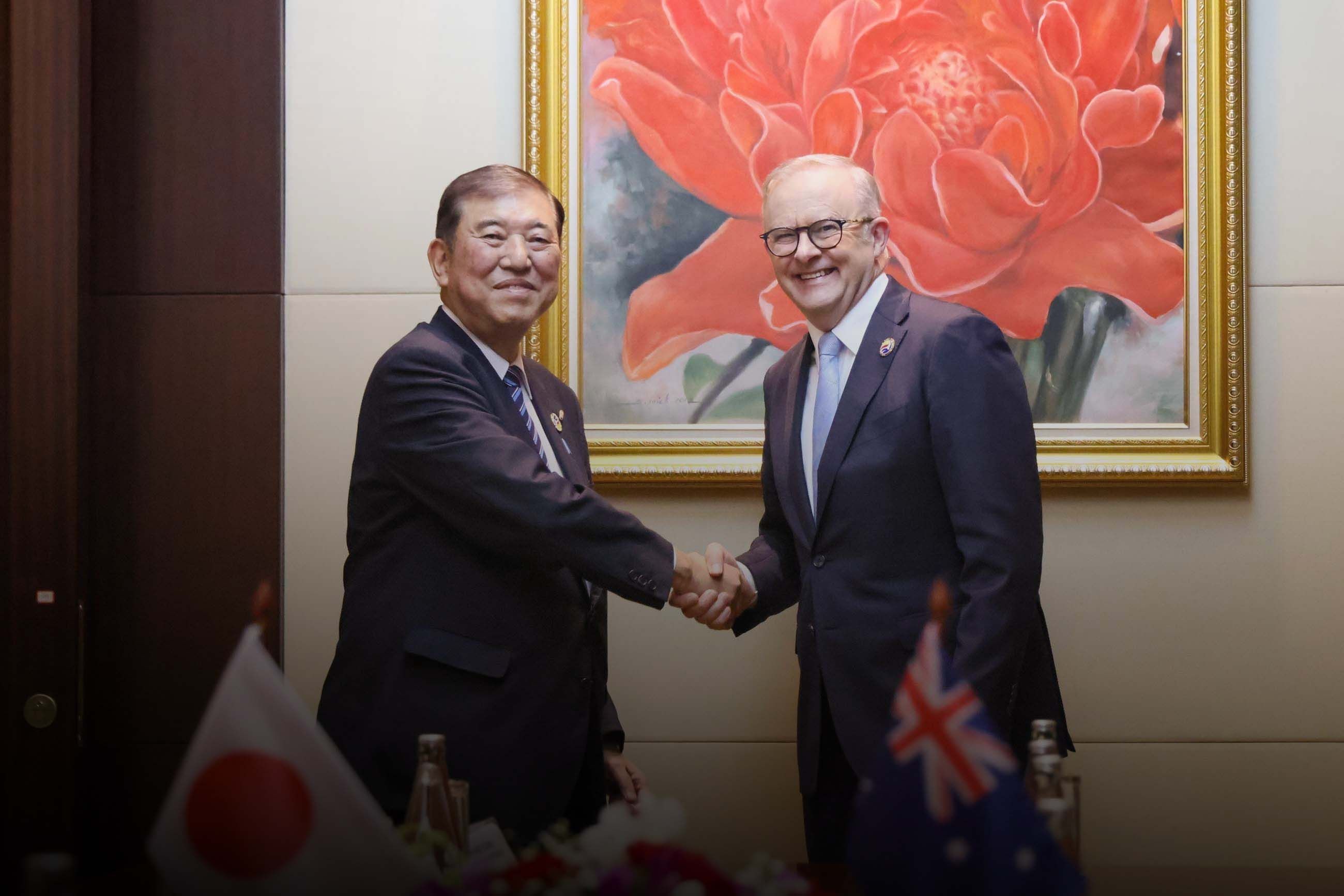 Two leaders shake hands as they pose for a photograph.