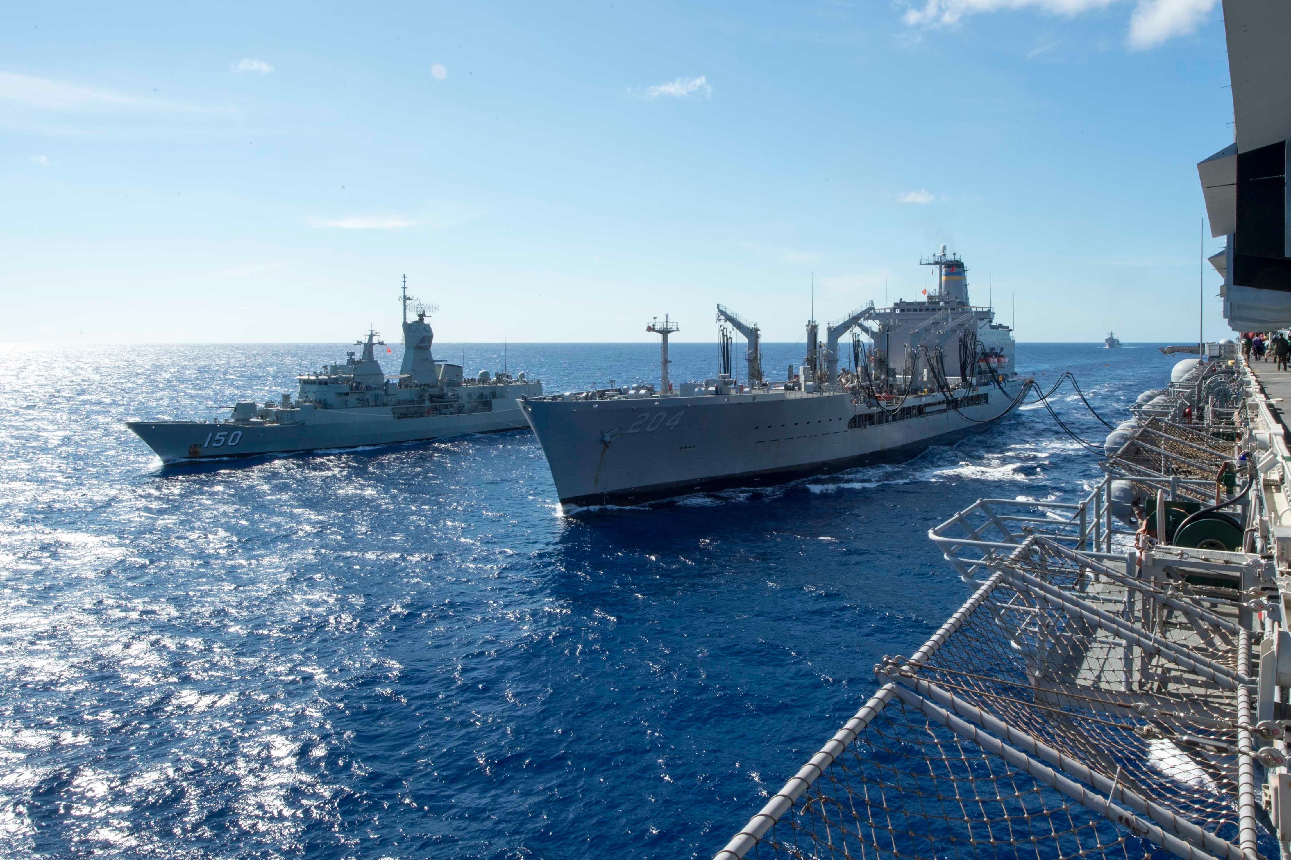 The fleet replenishment oiler USNS Rappahannock refuels the amphibious assault ship USS Bonhomme Richard and the Royal Australian Navy frigate helicopter HMAS Anzac during a replenishment-at-sea