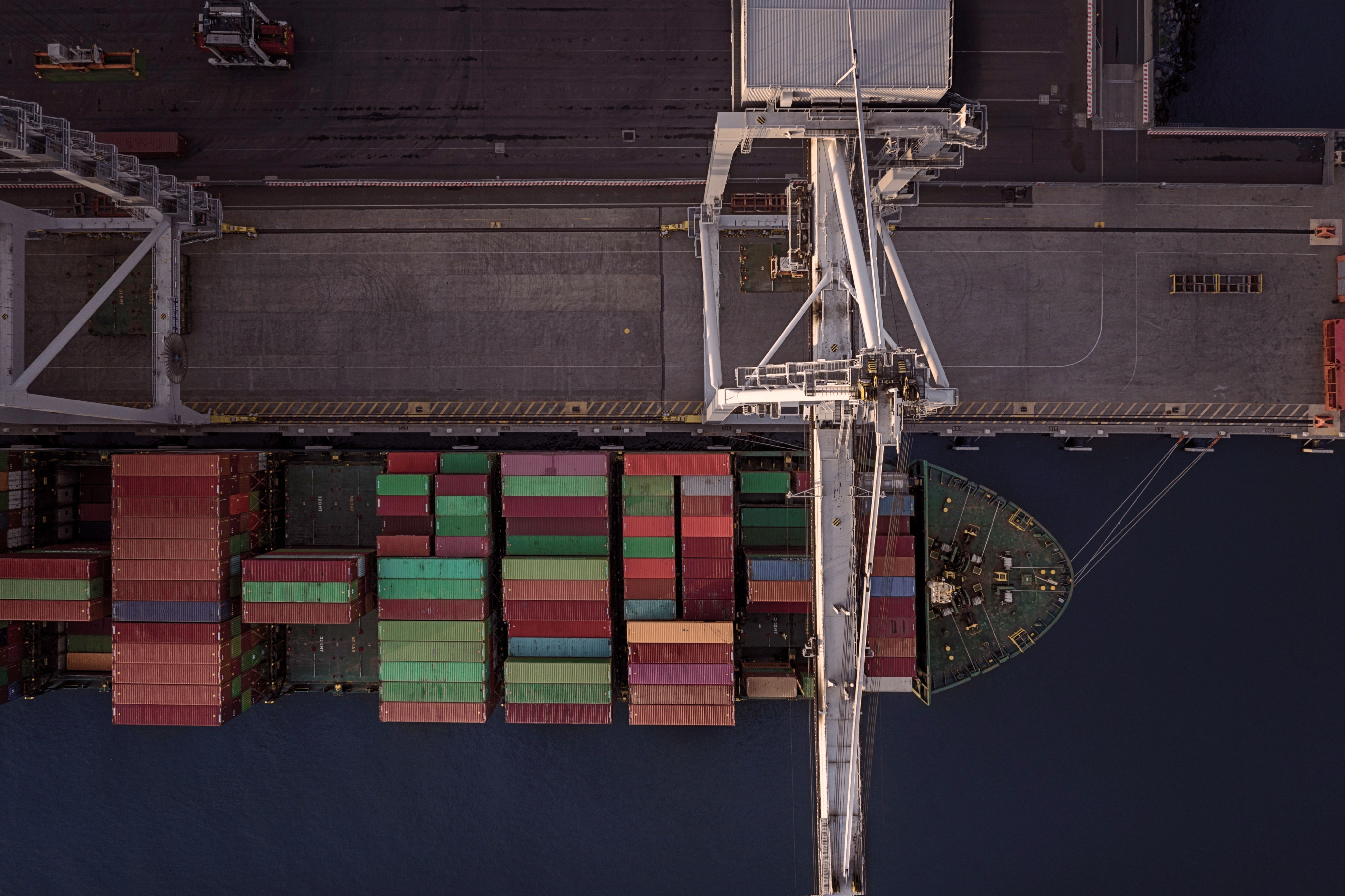 A birds eye view of a cargo Boat anchored in the Port Melbourne cargo facilities, it is being loaded with colourful containers, Drone view, Port Melbourne, Victoria, Australia