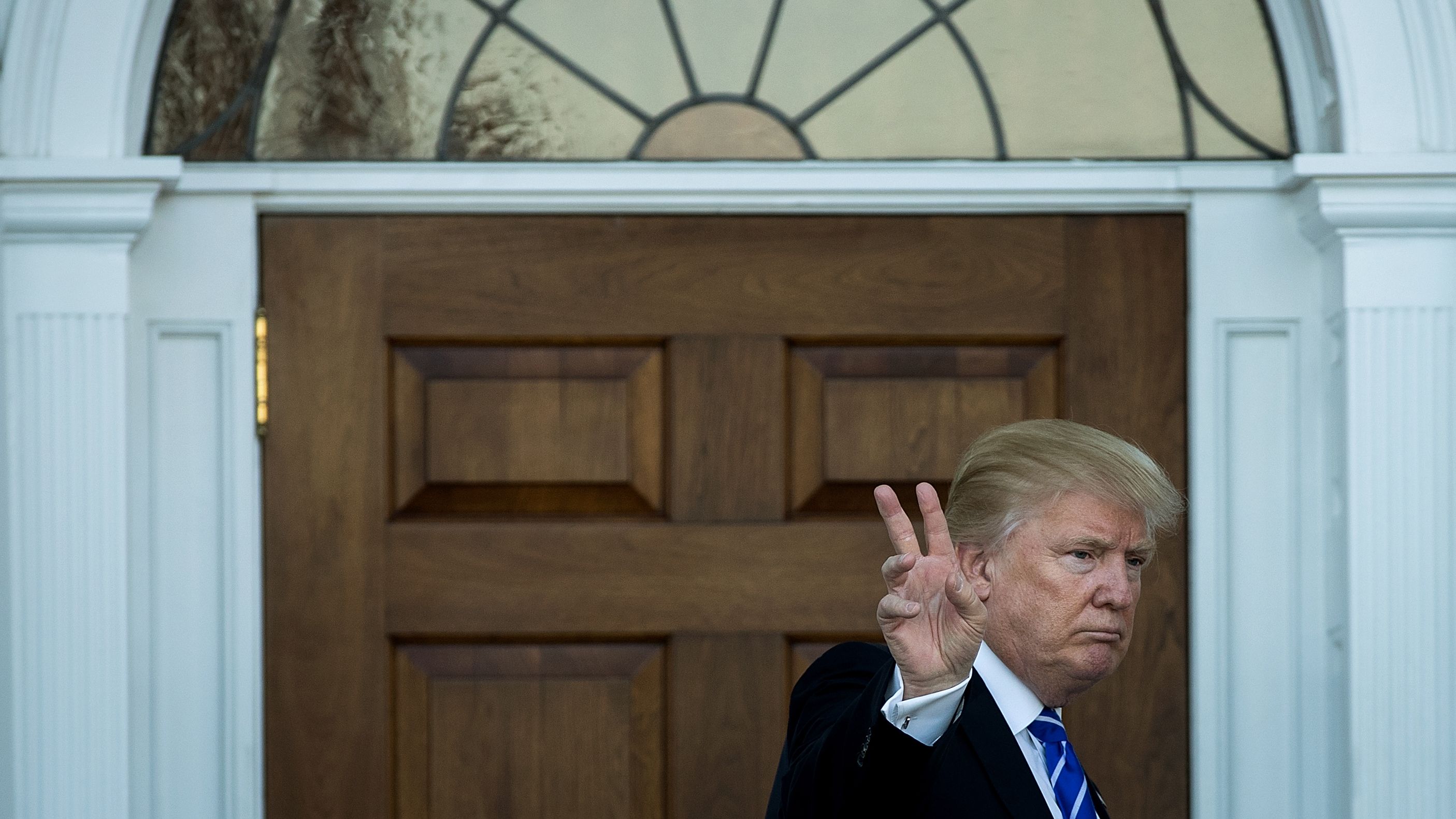 President-elect Donald Trump gives the peace sign after his meeting with Betsy DeVos  at Trump International Golf Club, November 19, 2016 in Bedminster Township, New Jersey. 