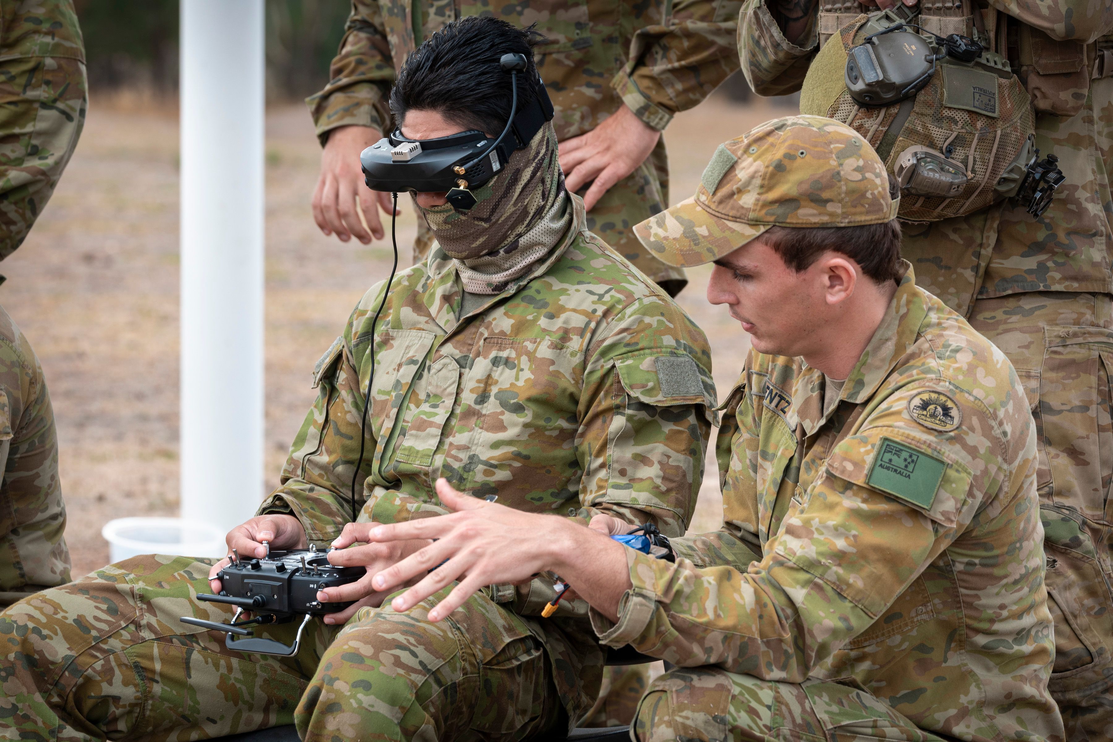 An Australian Army instructor coaches a trainee to fly a drone using First Person View google during the Modify and Operate Attack Drone (FPV) Course at Puckapunyal Military Area, Victoria.