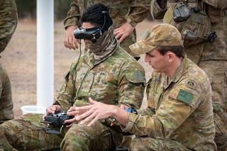An Australian Army instructor coaches a trainee to fly a drone using First Person View google during the Modify and Operate Attack Drone (FPV) Course at Puckapunyal Military Area, Victoria.