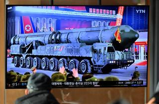A man watches a television screen showing a news broadcast with an image of a North Korean military parade held in Pyongyang, February 2023.