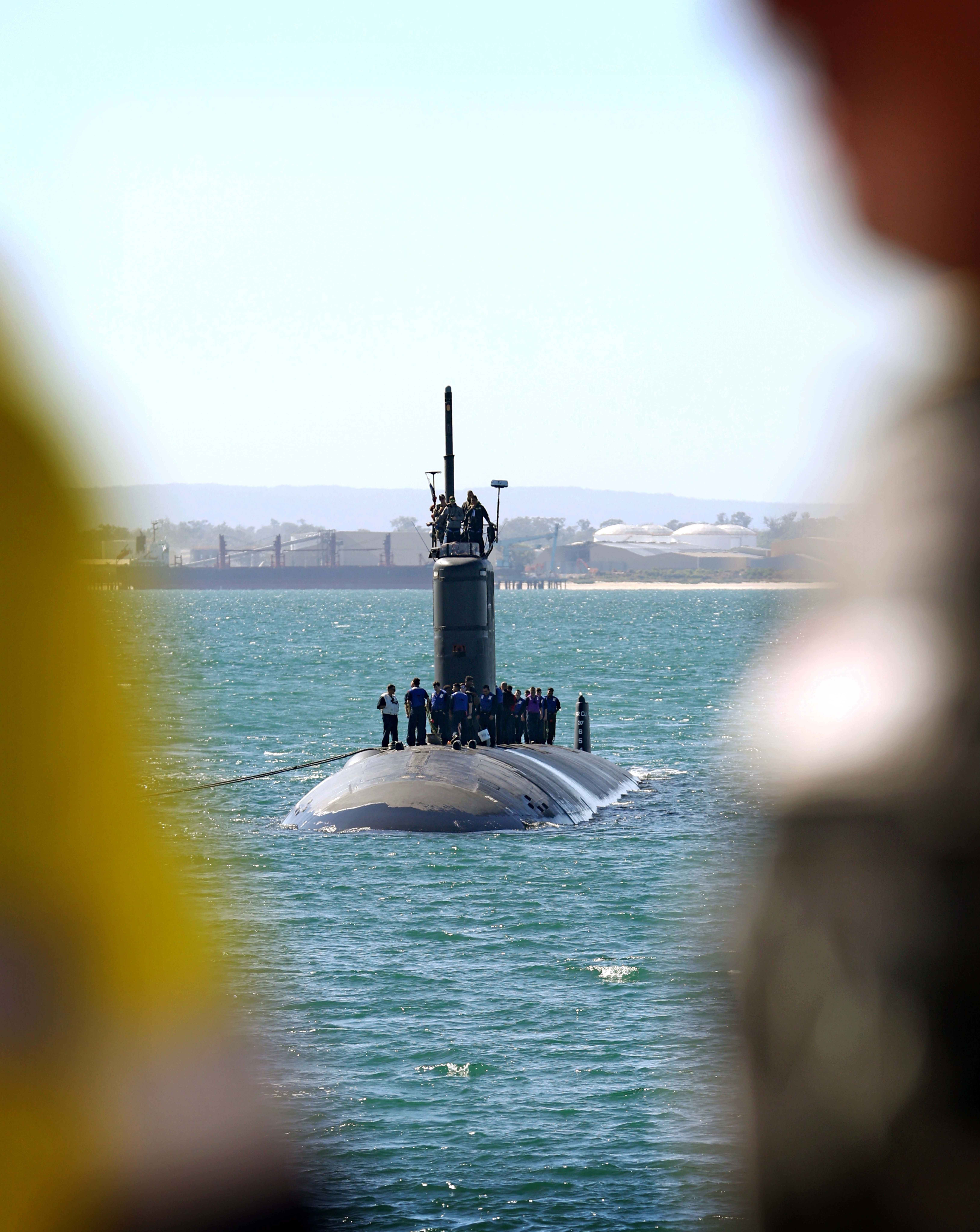 Submarine coming into port, with sailors standing on top.
