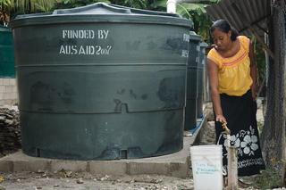 A woman collects water from a tank funded by then AusAID in Kiribati