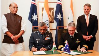 Indian Defence Minister, Shri Rajnath Singh (L) and Deputy Prime Minister and Minister for Defence, Richard Marles (R) witness Vice Chief of the Naval Staff of India, Sanjay Vatsayan (2nd-L) and Australia's Deputy Chief of Navy Matt Buckley (2nd-R) signing defence cooperation documents to Australia for his first official visit on October 09, 2025 in Canberra