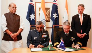 Indian Defence Minister, Shri Rajnath Singh (L) and Deputy Prime Minister and Minister for Defence, Richard Marles (R) witness Vice Chief of the Naval Staff of India, Sanjay Vatsayan (2nd-L) and Australia's Deputy Chief of Navy Matt Buckley (2nd-R) signing defence cooperation documents to Australia for his first official visit on October 09, 2025 in Canberra