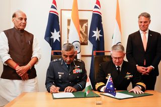 Indian Defence Minister, Shri Rajnath Singh (L) and Deputy Prime Minister and Minister for Defence, Richard Marles (R) witness Vice Chief of the Naval Staff of India, Sanjay Vatsayan (2nd-L) and Australia's Deputy Chief of Navy Matt Buckley (2nd-R) signing defence cooperation documents to Australia for his first official visit on October 09, 2025 in Canberra