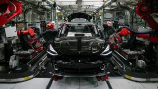 Robotics arms assemble a vehicle at the Tesla factory in Fremont, California, 2018