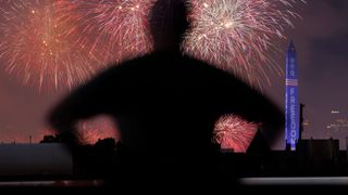 A person watches fireworks from the Freedom 250 Salute to America Independence Day celebration go off behind the Washington Monument during a thunderstorm on July 5, 2026 in Washington, DC.