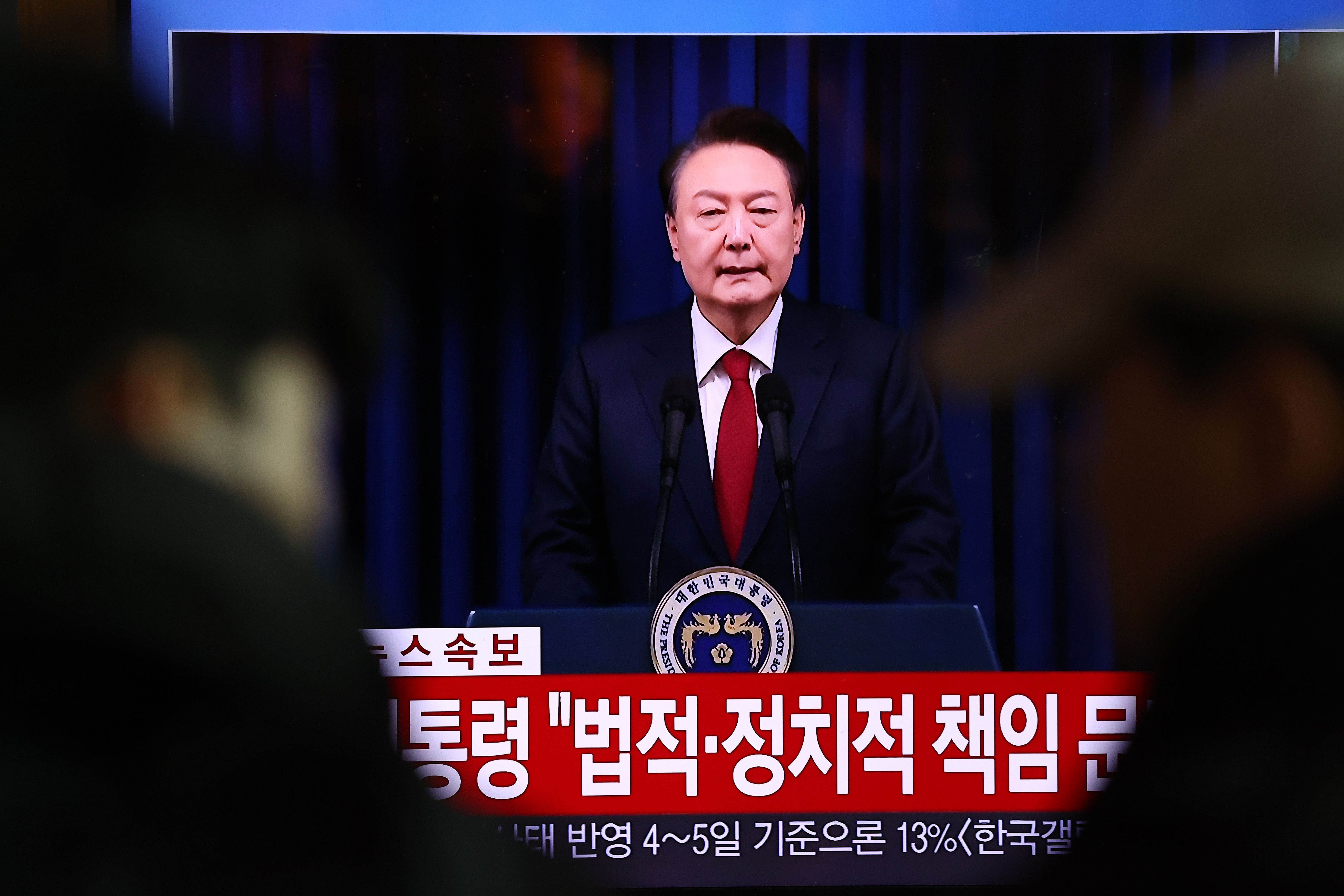 A screens shows footage of South Korean President Yoon Suk Yeol delivering an address to the nation at Seoul station on December 07, 2024 in Seoul, South Korea. South Korea is facing significant political turmoil after President Yoon Suk-yeol declared emergency martial law, accusing opposition parties of destabilizing governance and sympathizing with North Korea.