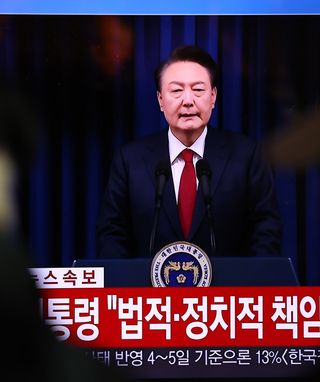 A screens shows footage of South Korean President Yoon Suk Yeol delivering an address to the nation at Seoul station on December 07, 2024 in Seoul, South Korea. South Korea is facing significant political turmoil after President Yoon Suk-yeol declared emergency martial law, accusing opposition parties of destabilizing governance and sympathizing with North Korea.