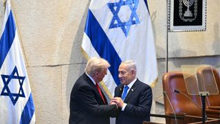 U.S. President Donald Trump (L) holds hands and speaks with Israeli Prime Minister Benjamin Netanyahu at the Israeli parliament, the Knesset, on October 13, 2025 in Jerusalem. President Trump is visiting the country hours after Hamas released the remaining Israeli hostages captured on Oct. 7, 2023, part of a US-brokered ceasefire deal to end the war in Gaza.