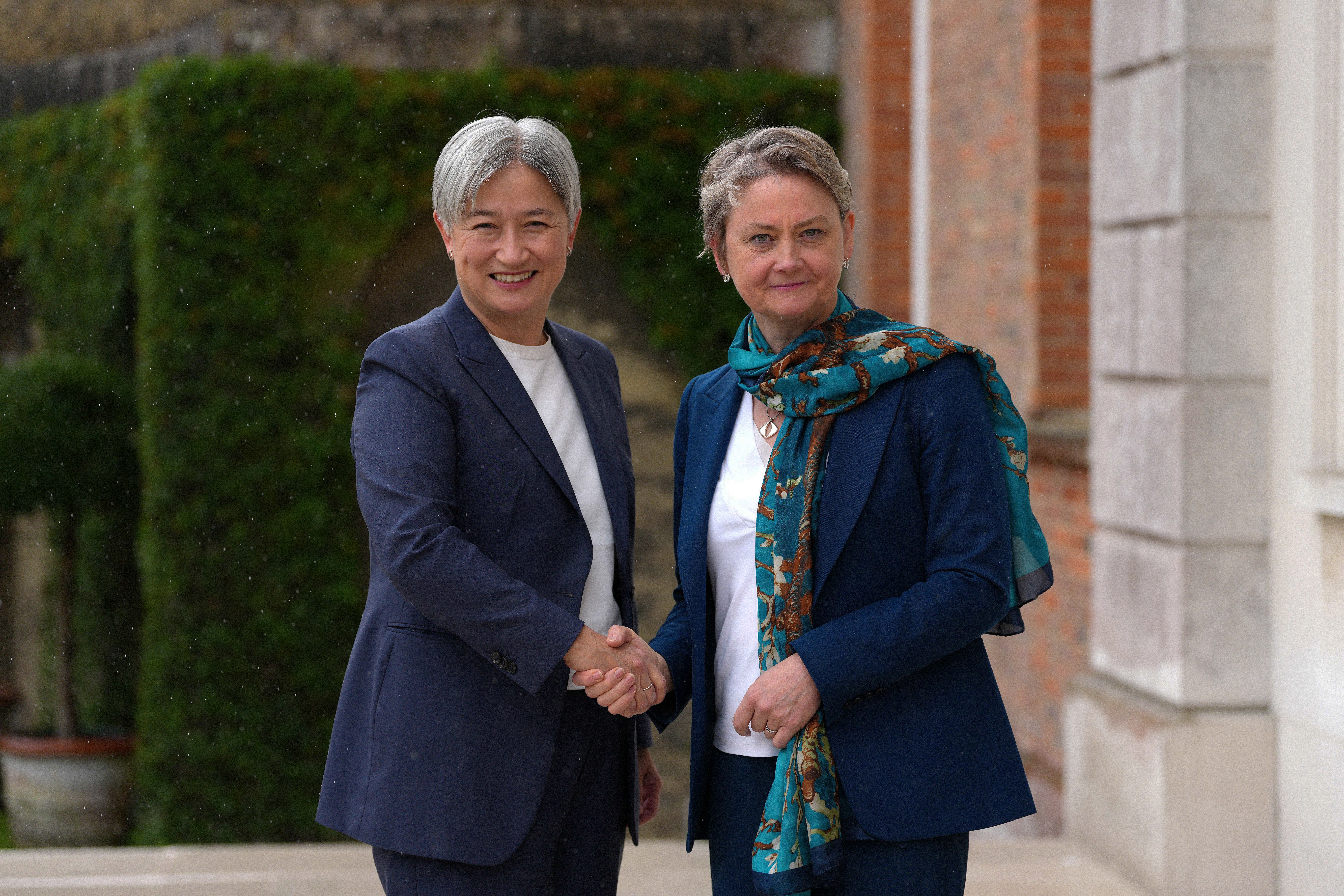 Two people shake hands and smile toward the camera.