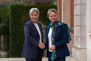 Two people shake hands and smile toward the camera.