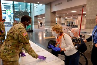 A US Army National Guard Soldier helps travellers register their arrival at TF Green International Airport in Warwick, Rhode Island on 30 March 2020, during the novel coronavirus (COVID-19) outbreak
