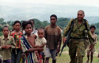 Lieutenant Commander Jason Bishop from the Australian 108 Field Battery with local children in an Operation Annandale patrol of mountains near Suai, Timor-Leste, 2004