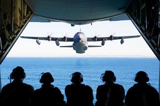 US and Australian airmen watch an MC-130J Air Commando II fly off the coast of Australia, July 2021