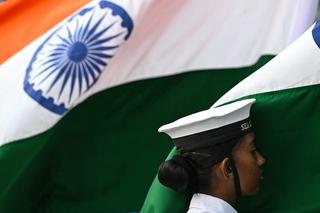 A sea cadet of the Indian Navy stands beside the country’s national flag during Navy Day celebrations at the Gateway of India in Mumbai, December 2023