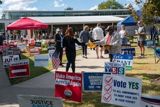 People walk past campaign signs as they go to participate in early voting for the midterm elections on October 25, 2026 in Cary, North Carolina.