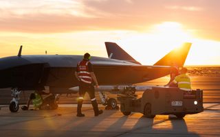 An MQ-28A Ghost Bat is loaded with a NAIM-120 inert air-to-air missile variant at the ordnance loading area during Trial Kareela at RAAF Base Woomera.