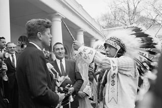 President John F. Kennedy is presented a ceremonial pipe by Edison Realbird from the Montana Crow Indian Agency during a visit to the White House by 100 members of the National Congress of American Indians.
