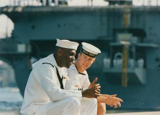 An American sailor speaks to an Australian sailor