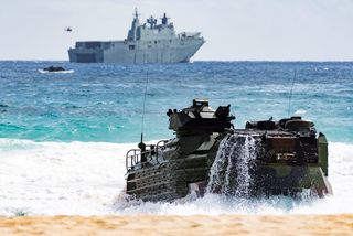 A US Marine Corps Amphibious Assault Vehicle hits the beach at Kaneohe Bay, Hawaii after disembarking HMAS Adelaide during Exercise RIMPAC 2018