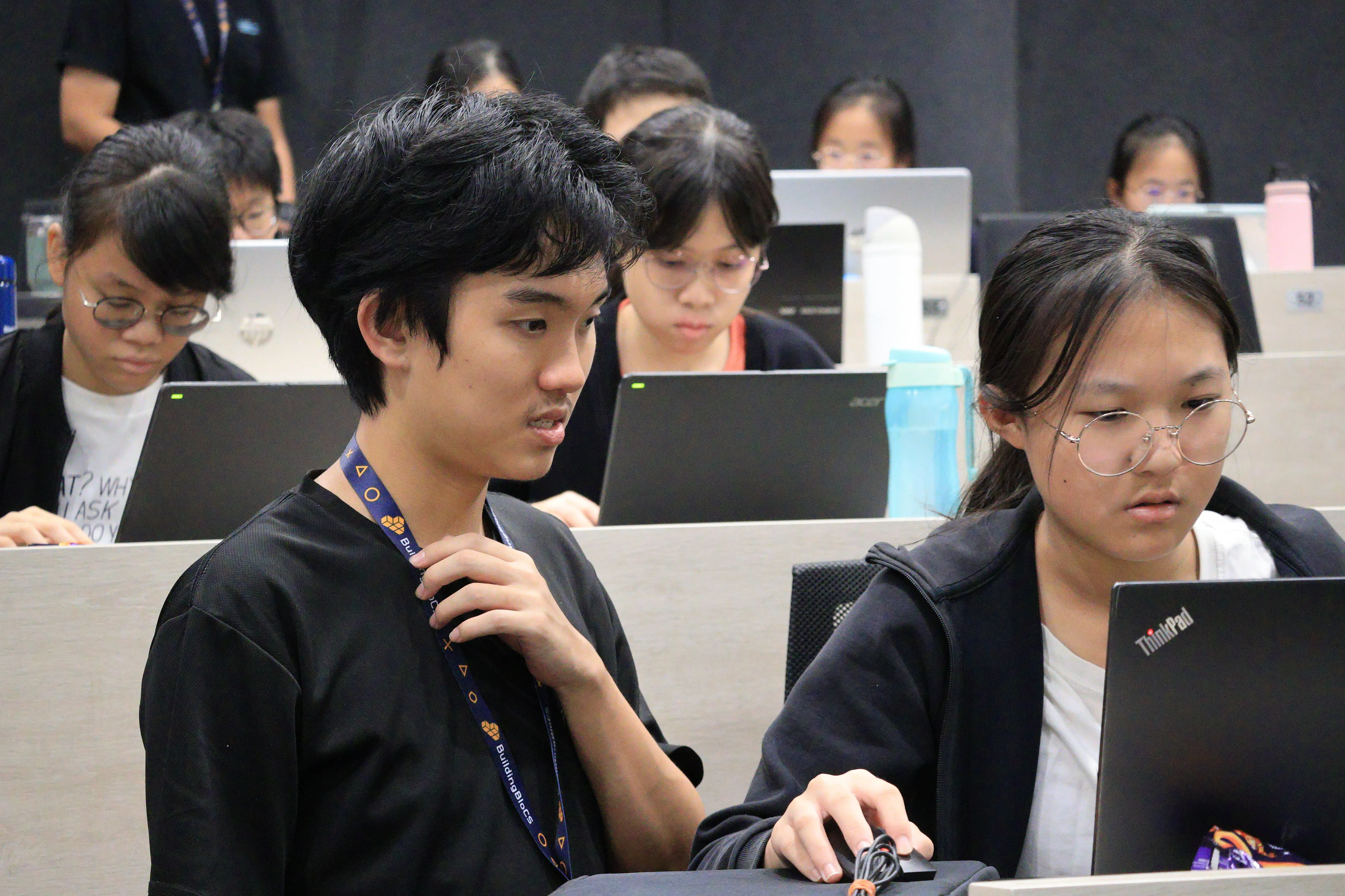 Two students discussing code together on a laptop at BuildingBloCS workshop