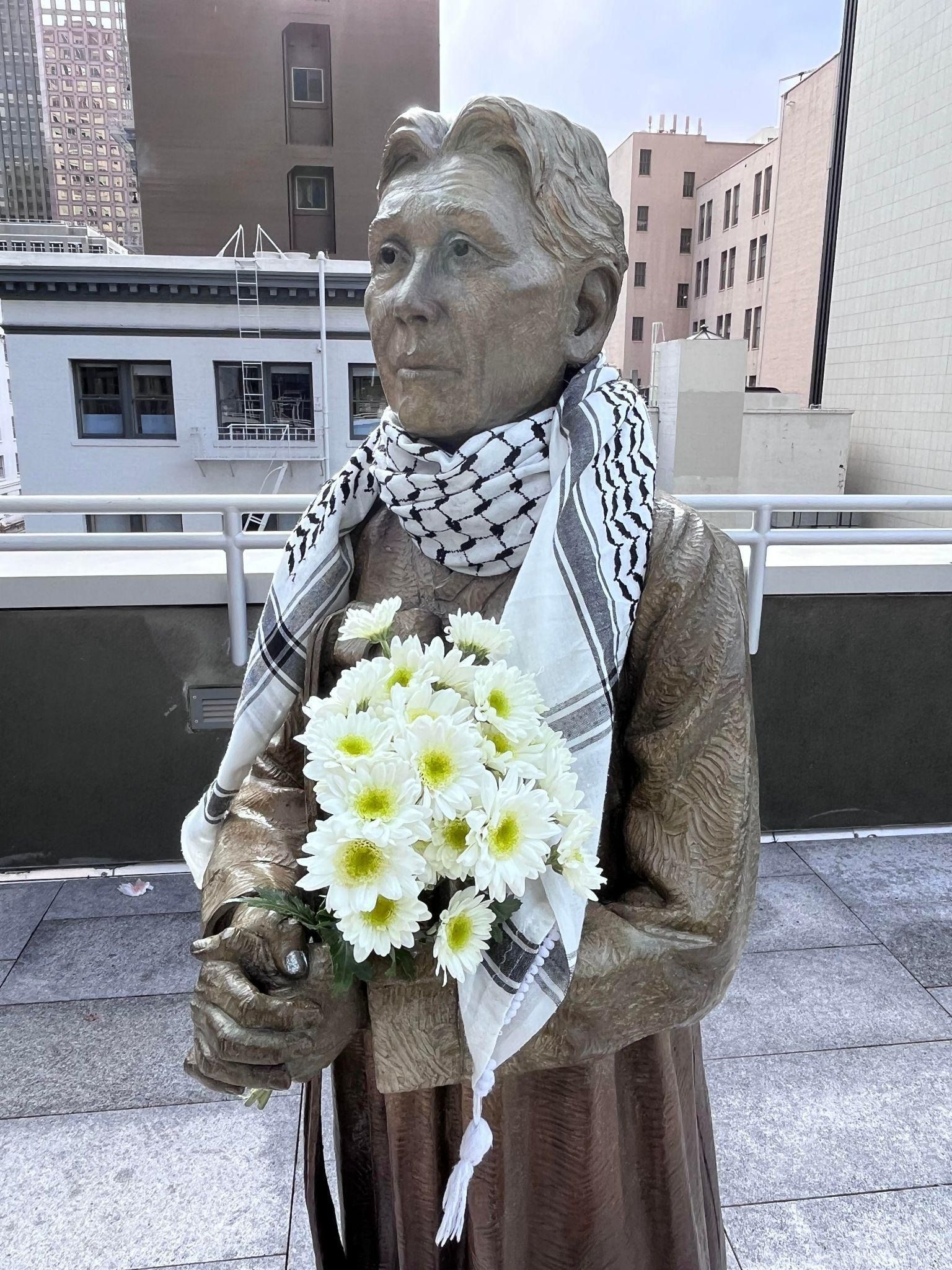 The memorial statue of Kim Haksun, one of the first “comfort women” survivors who spoke up in 1992 demanding accountability from the Japanese Government. The “Comfort Women” Justice Coalition built the statue in San Francisco’s China Town in 2017. During the ongoing Israel/US genocide against Palestine, activists dressed the statue with a Palestinian Kuffiya and flowers to show cross-movement solidarity. Photo credit: Tomomi Bae Kinukawa