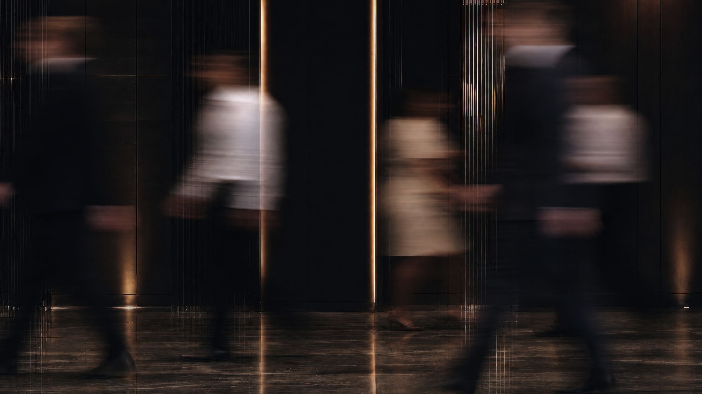 Blurred figures moving through a dark lobby