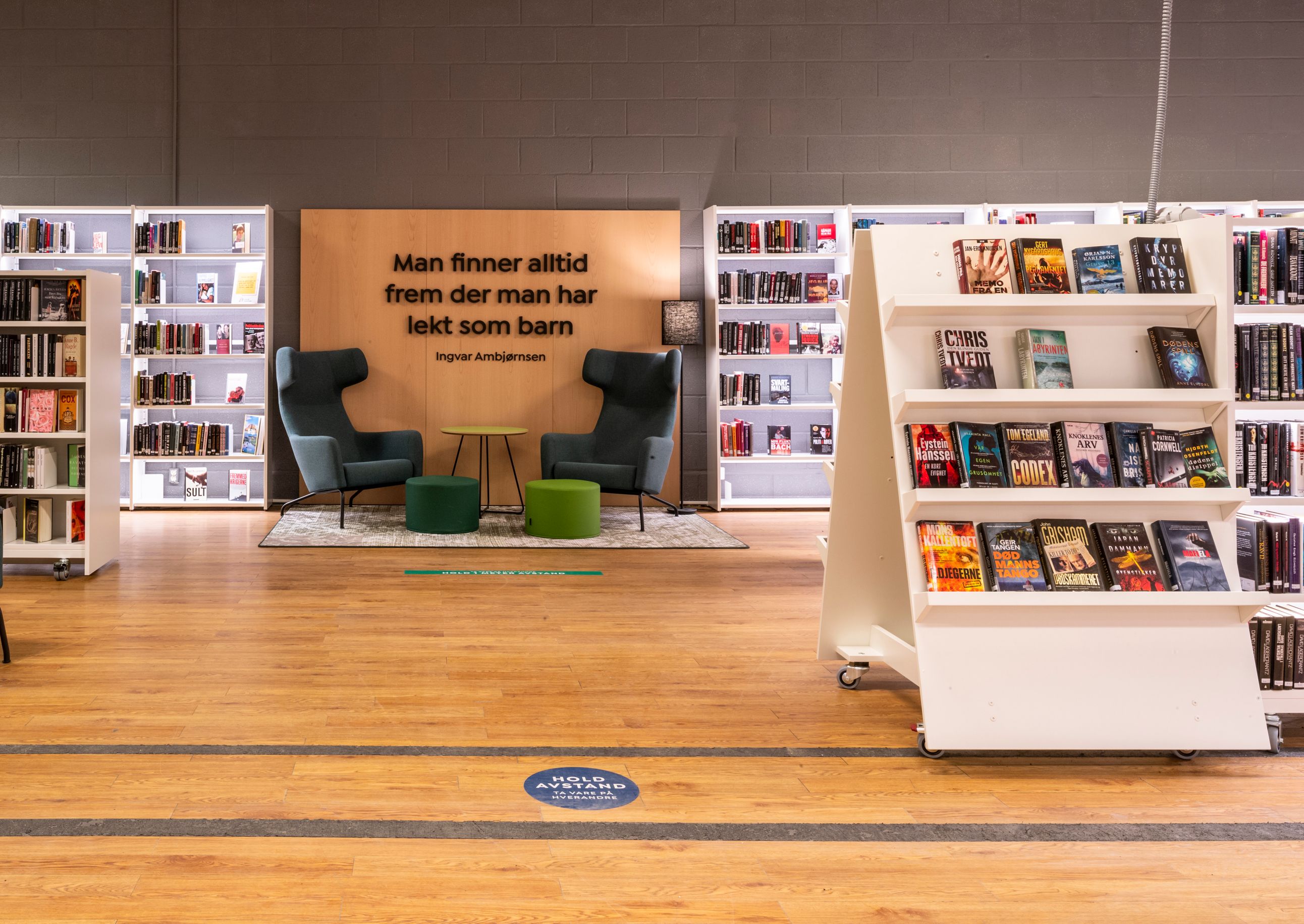 et bibliotek med stoler, bord og bokhyller.
